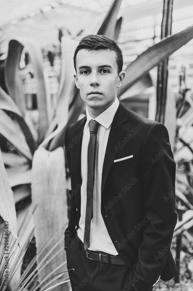 Φωτογραφία Serious man portrait handsome groom in a wedding suit and tie is standing on the background of Botanical garden full of cactus