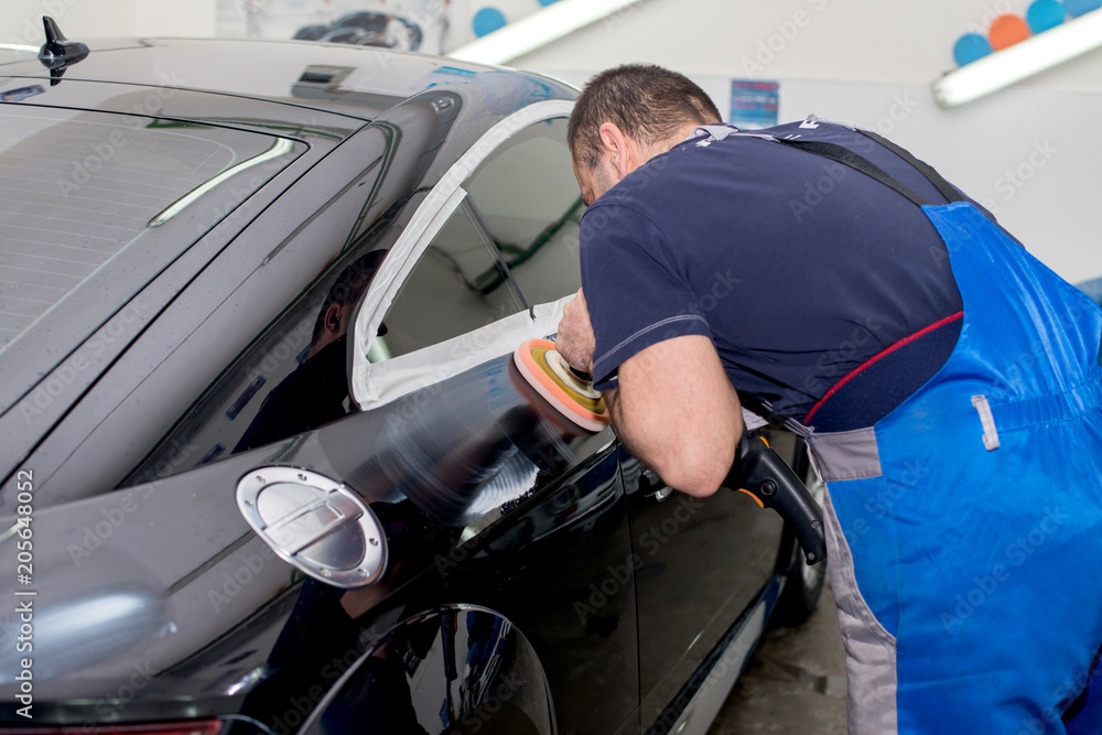 A man polishes a black car with a polisher A man polishes a black car with a polisher