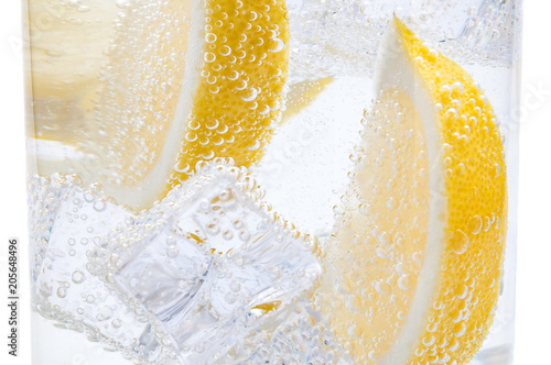 In a glass with cubes of melting ice slices of a juicy yellow lemon.