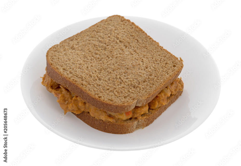Curry flavored tuna sandwich on a plate isolated on a white background.
