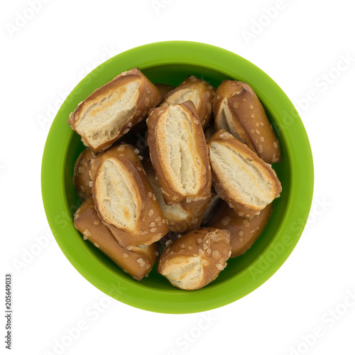 Top view of bite size sourdough pretzels in a green bowl isolated on a white background.