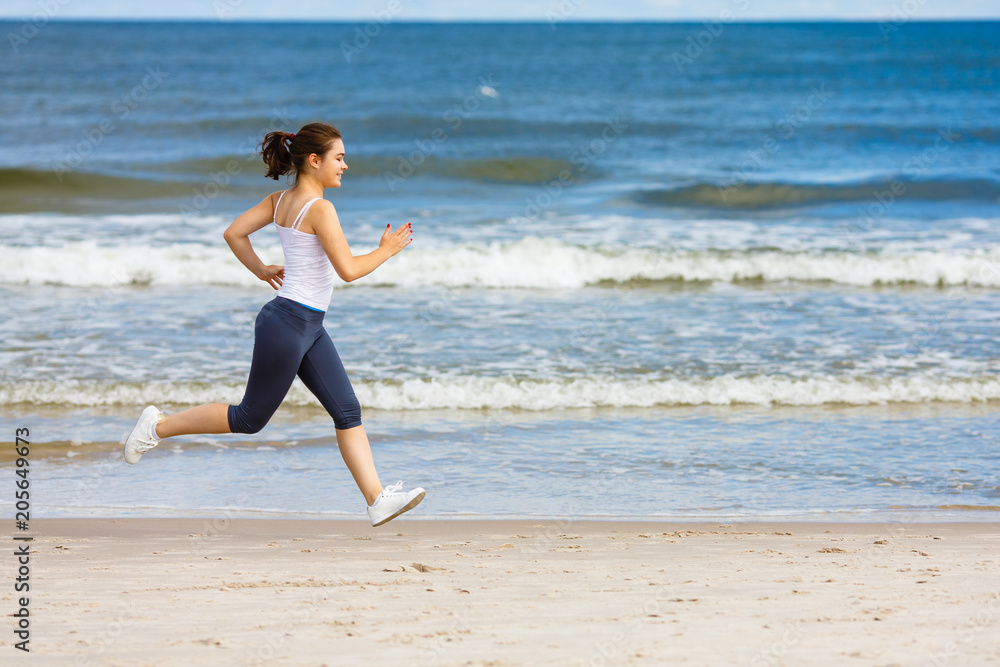 Young woman running, jumping on beach