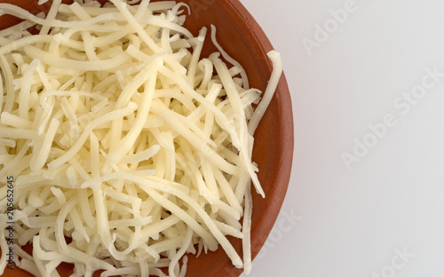 Top close view of sharp white cheddar cheese in a small bowl on a counter top.