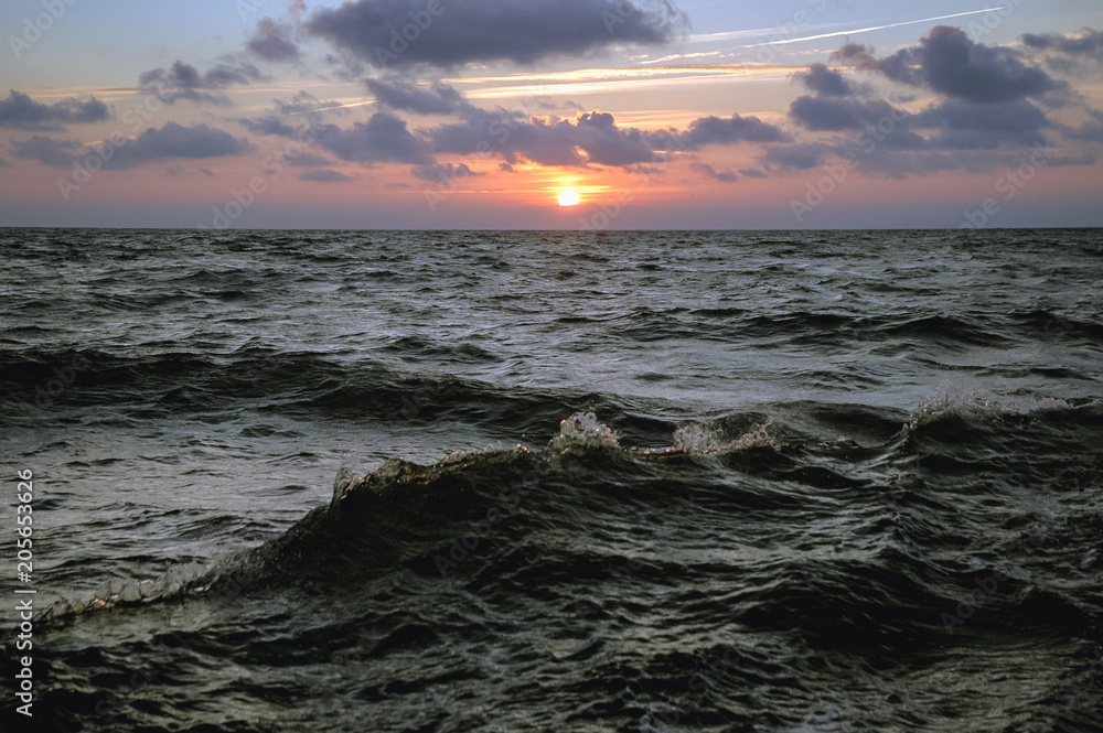 Sunset over rough water of Baltic Sea seen from a tourist boat in Leba town, Poland