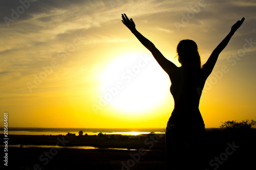 silhouette of a girl raising hands to the sky after physical training, a woman enjoying the sunset
