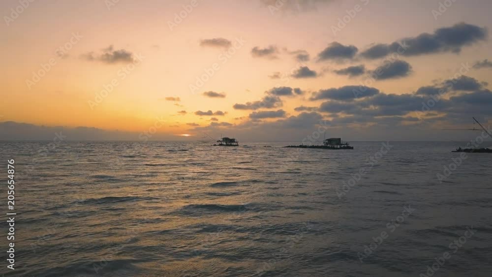 Vista aerea di sagome dei trabucchi sul mare per la pesca del pesce con pescatori alle ultime luci del tramonto. Vista aerea di sagome dei trabucchi sul mare per la pesca del pesce con pescatori alle ultime luci del tramonto.