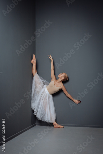 Fototapeta Naklejka Na Ścianę i Meble -  Pretty graceful dancer standing and making stretching exercise.