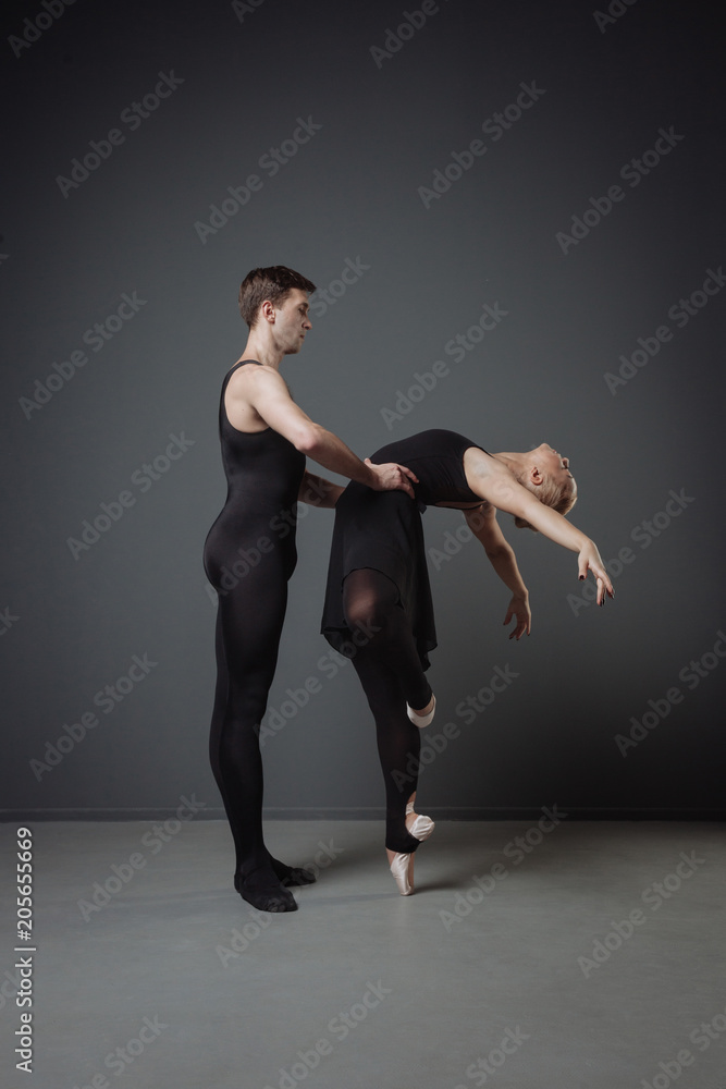 Graceful ballet dancers training on grey background