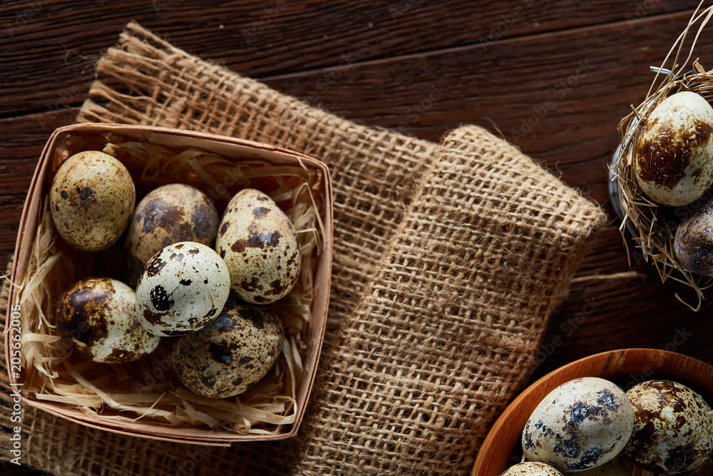 Rustic still life with quail eggs in bucket, box and bowl on a linen napkin over wooden background, selective focus Rustic still life with quail eggs in bucket, box and bowl on a linen napkin over wooden background, selective focus