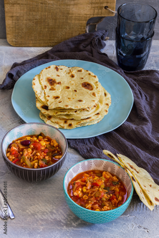 Tortillas with chili con carne. Grey background blue and grey bowls, plates. Tortillas with chili con carne. Grey background blue and grey bowls, plates.