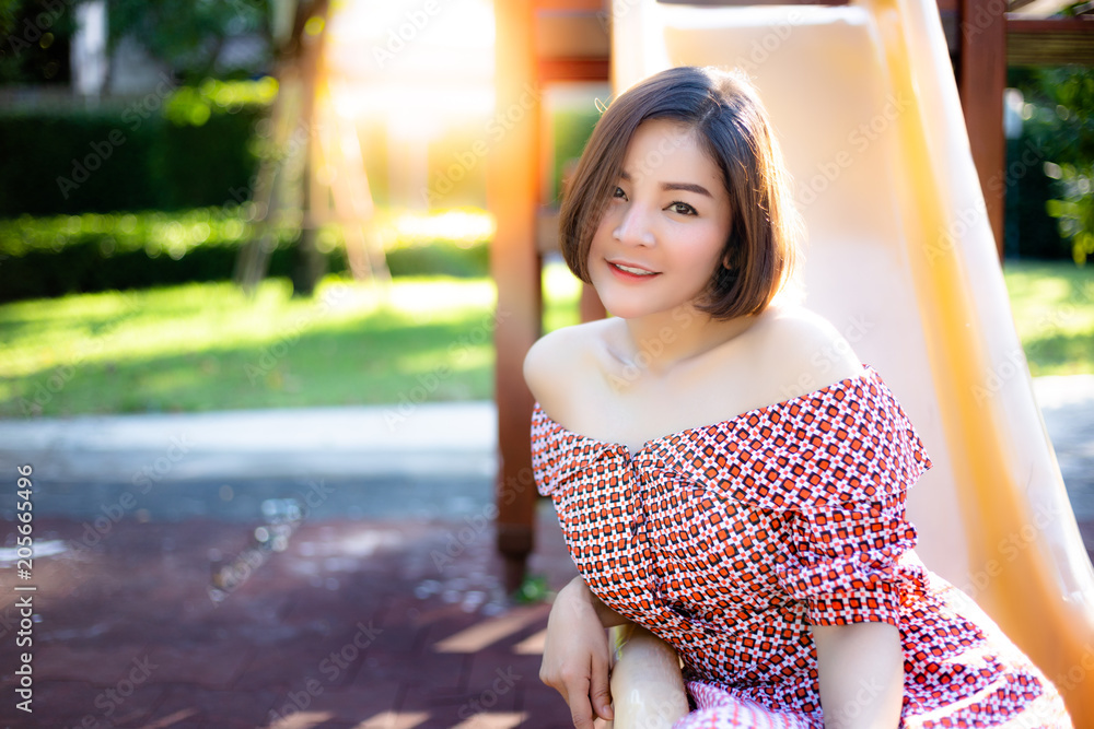Beautiful woman has a good mood when gorgeous girl comes to the park. Charming beautiful woman sit on a slider at playground. Glamour asian girl feels happy. She wears beautiful dress in summer season Beautiful woman has a good mood when gorgeous girl comes to the park. Charming beautiful woman sit on a slider at playground. Glamour asian girl feels happy. She wears beautiful dress in summer season