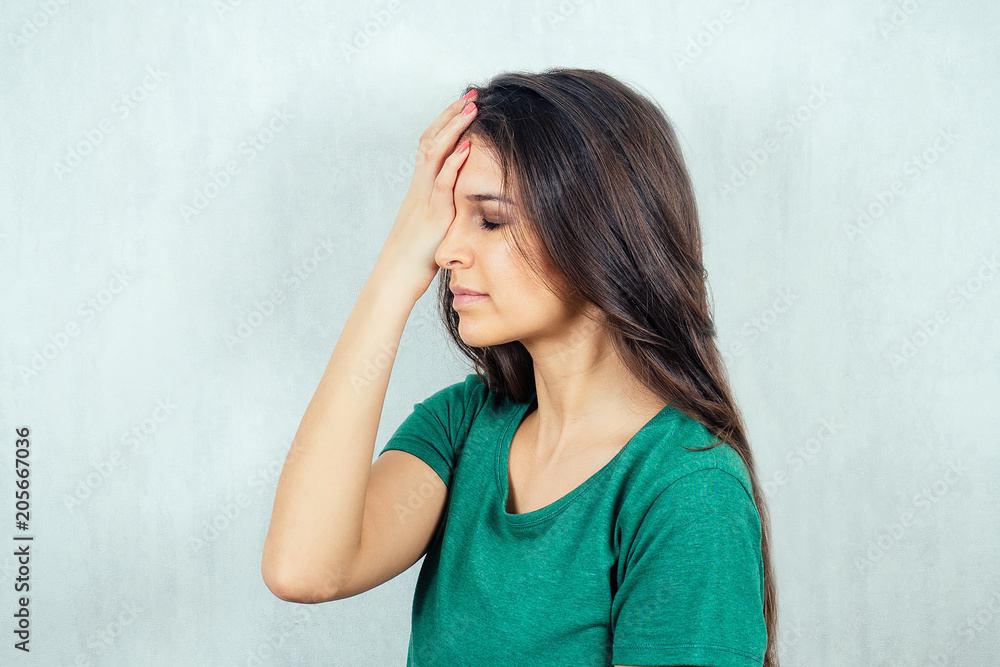 Portrait of a young and beautiful brunette holding her hands behind her head. concept of a headache of imigrains Portrait of a young and beautiful brunette holding her hands behind her head. concept of a headache of imigrains