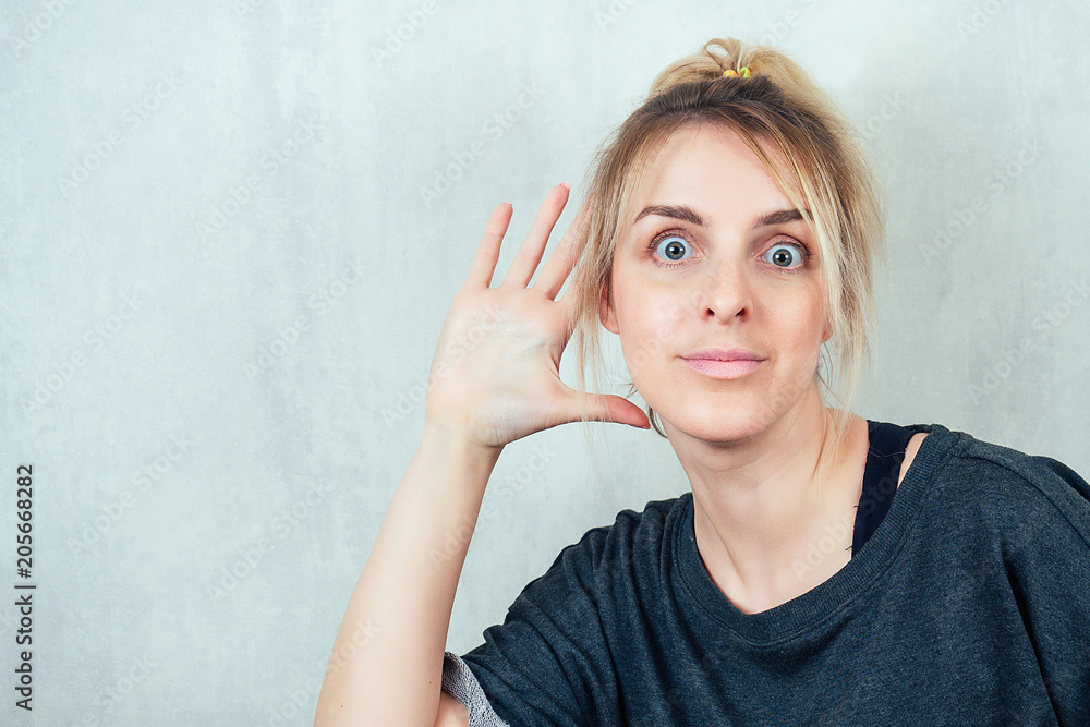 portrait of a young blonde woman holding her hand by the ear. the concept of eavesdropping and gossip portrait of a young blonde woman holding her hand by the ear. the concept of eavesdropping and gossip