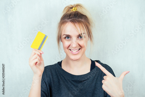 Portrait of a young and beautiful blonde holding a credit card in her hand. concept of shopping and credit