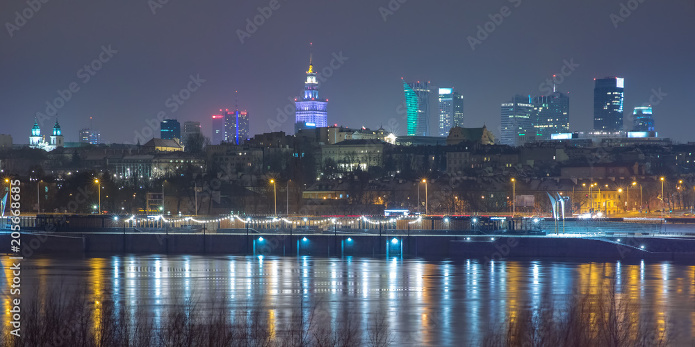 festively lit modern skyscrapers and Old Town with reflection in the Vistula Riverat night, Warsaw, Poland.