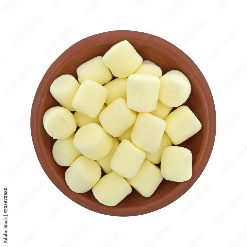 Top view of yellow miniature marshmallows in a small bowl isolated on a white background.