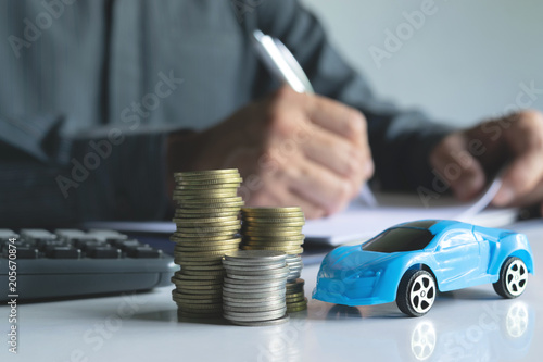 Men are Saint documents about cars with some coins calculator and car toy on desk