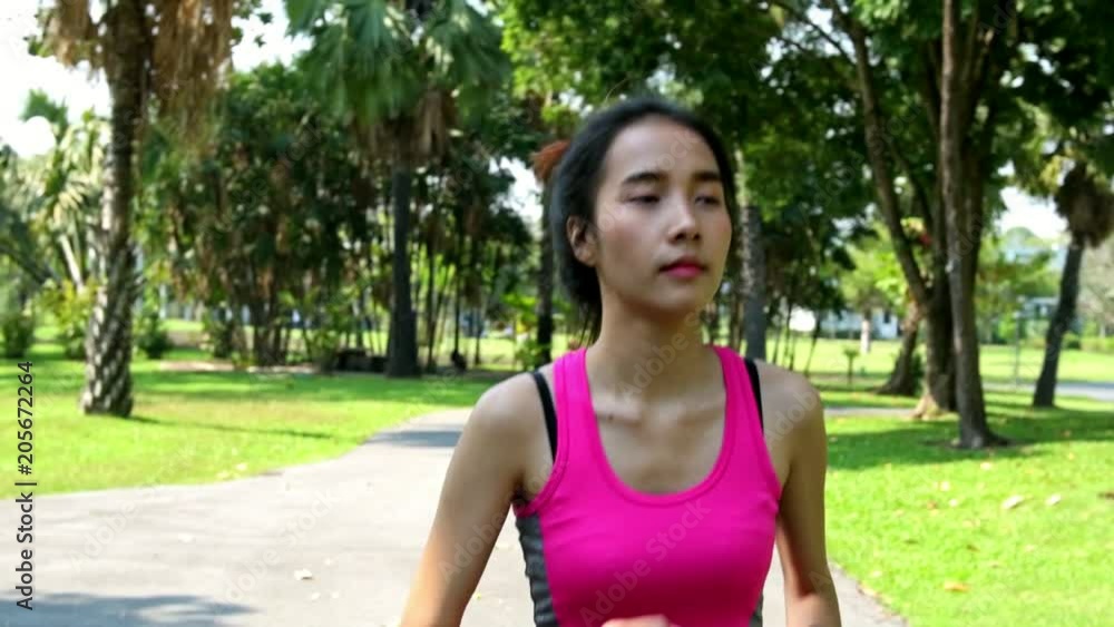 Slow motion of asian woman running in park. Running towards camera, handheld shot. Slow motion of asian woman running in park. Running towards camera, handheld shot.