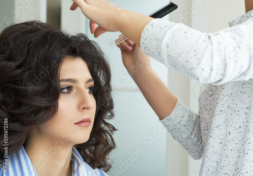 Closeup view of the hand and comb of a hairstylist combing a new hairstyle on a customer head in hair salon.