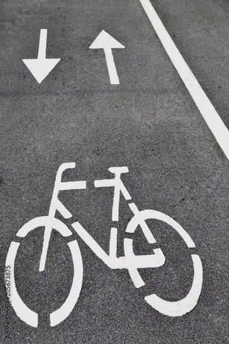 White arrows and bicycle sign on grey lanes road.