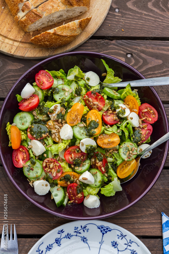 Lettuce and tomatoes salad on wooden table. In the garden.
Lettuce and tomatoes salad on wooden table. In the garden.