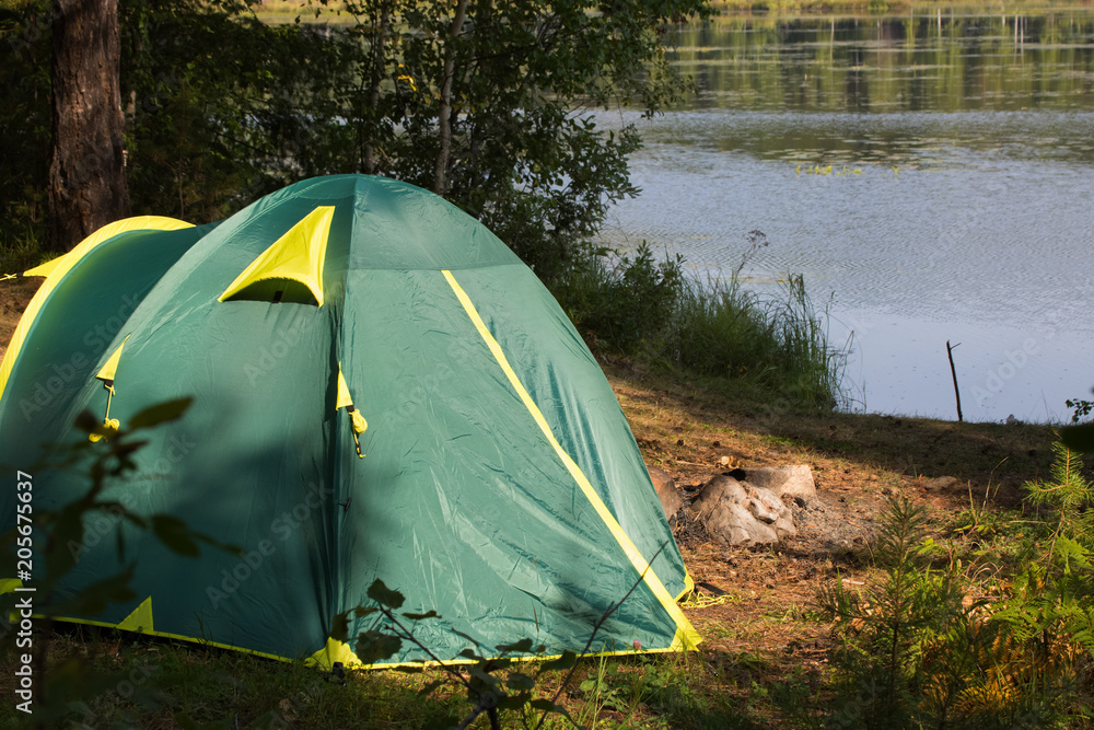 tent on the shore of a forest lake