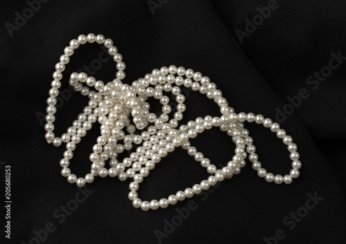 Long sting of fake pearls on a black fabric background.