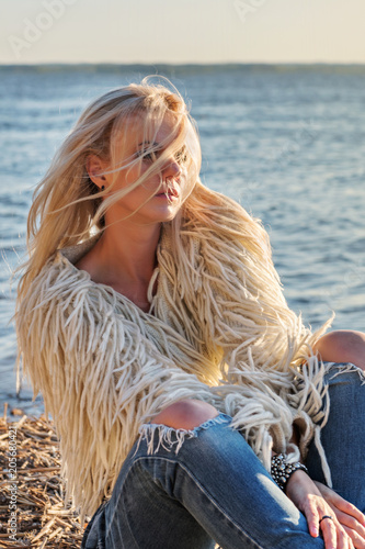 close-up portrait of a young attractive blond woman with hair scattered flying from the wind in the rays of a bright sun