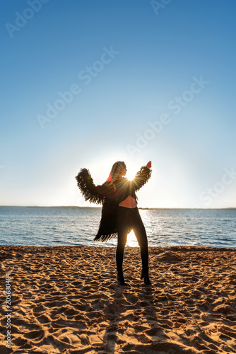 against the backdrop of the rising sun the silhouette of a dancing girl in fluttering black clothes like a bird photo