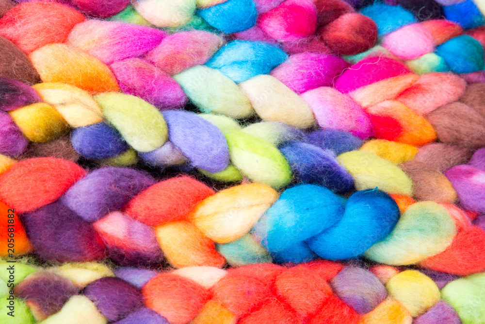 Bunt gefärbte und geflochtene Zöpfe aus Strickwolle nebeneinander aufgereiht Bunt gefärbte und geflochtene Zöpfe aus Strickwolle nebeneinander aufgereiht