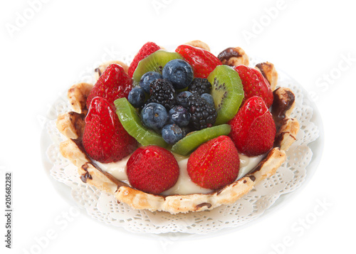 Fresh summer fruit tart with strawberries  kiwi  blueberries  boysenberries on a white doily on plate isolated on white background.