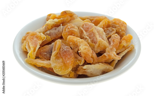 Dried mandarin orange slices in a small bowl isolated on a white background.