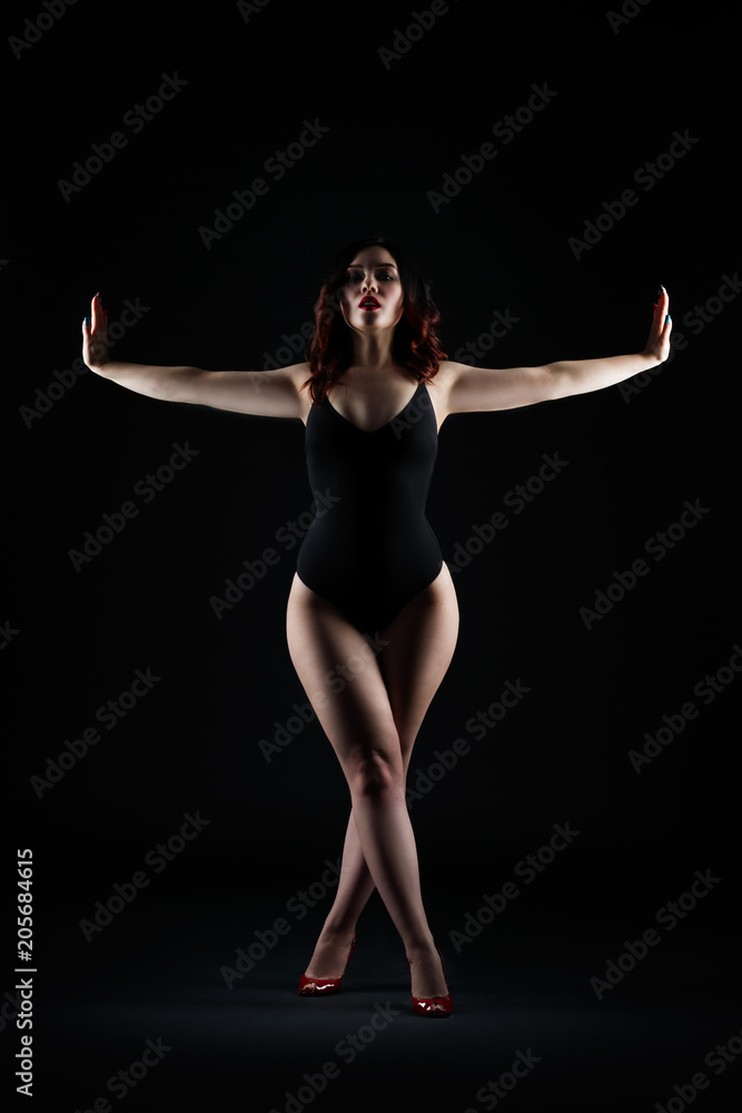 Beautiful sexy woman in bodysuit posing on black background, low key studio shot