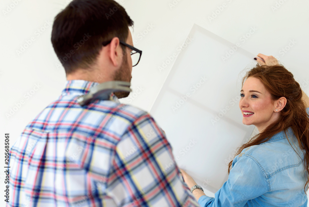 Obraz premium Couple in empty apartment measuring walls. Activities after relocation and renovation.