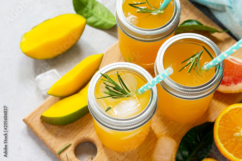 Refreshing summer cocktails made of citrus and mango, cold drink or a drink with ice on a black background. Concept of vegetarian food, fresh vitamins.