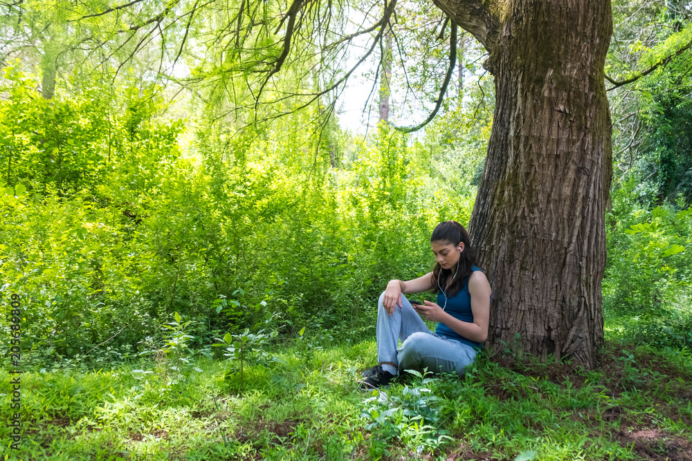 Beautiful girl resting in forest speak by cell phone, sports girl Beautiful girl resting in forest speak by cell phone, sports girl