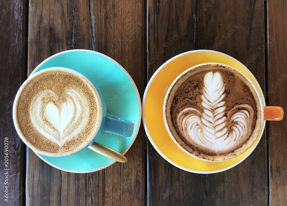 Two delicious aromatic americano coffee with foam in the shape of heart in a vintage blue cup and spoon on old wooden table, top view Two delicious aromatic americano coffee with foam in the shape of heart in a vintage blue cup and spoon on old wooden table, top view