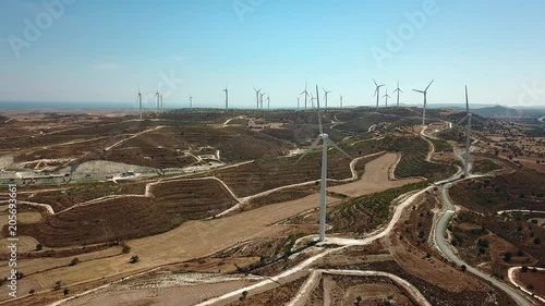 Aerial view of windmills in the mountains, wind power turbines. In the background, the sea.