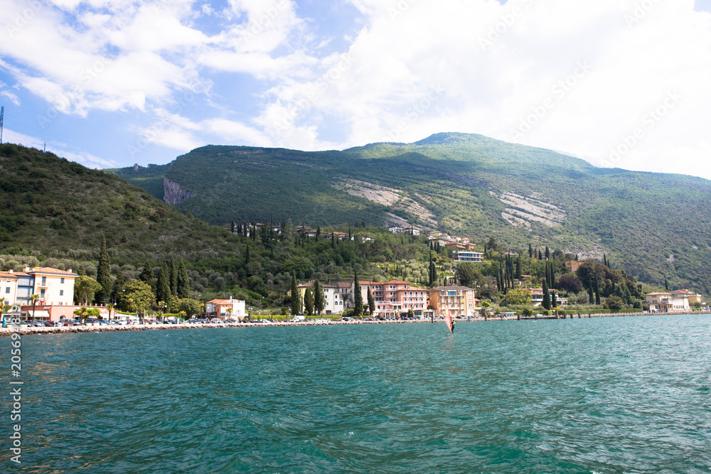 Panorama of the gorgeous Lake Garda surrounded by mountains and windsurfer pro-rider surfing in Torbole, Provincia di Trento, Trento-Alto Adige, Italy