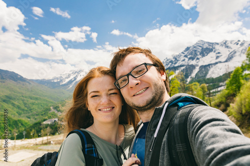 Travelling young couple take the selfie shot, smiling and happy. Summer mountains walk