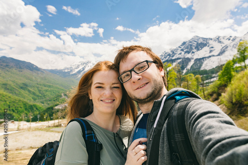 Travelling young couple take the selfie shot, smiling and happy. Summer mountains walk
