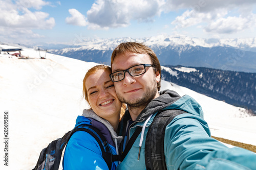 Travelling young couple take the selfie shot, smiling and happy, in the sport style clothes and backpack. Winter mountains sport
