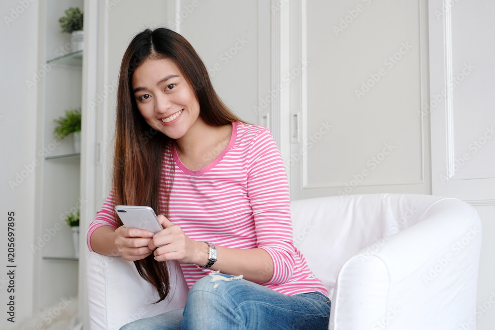 Young asian woman using smart phone with smiling, happy and relax emotion in white room background, people on phone, lifestyle Young asian woman using smart phone with smiling, happy and relax emotion in white room background, people on phone, lifestyle