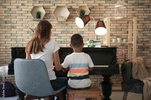 African-American boy with teacher learning to play piano indoors photo