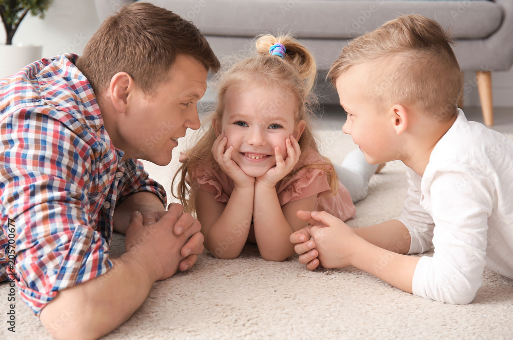 Cute little children and their father lying on cozy carpet at home Cute little children and their father lying on cozy carpet at home