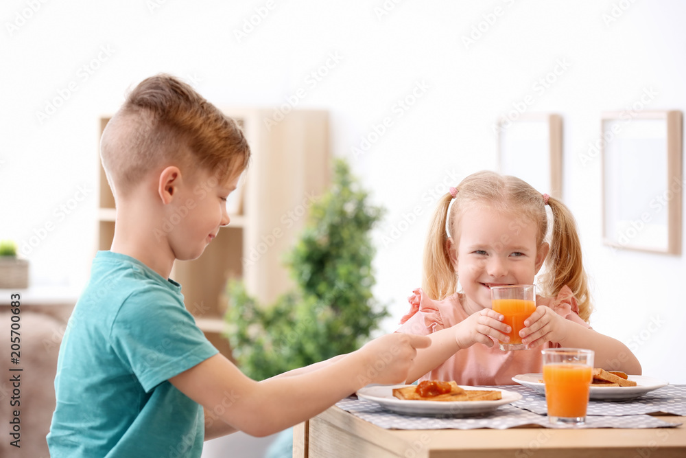 Adorable little children eating tasty toasted bread with jam at table Adorable little children eating tasty toasted bread with jam at table