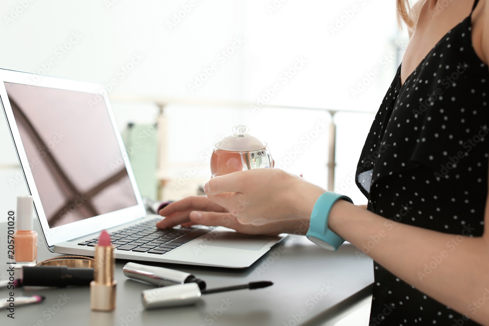 Young woman with makeup products using laptop at table. Beauty blogger Young woman with makeup products using laptop at table. Beauty blogger