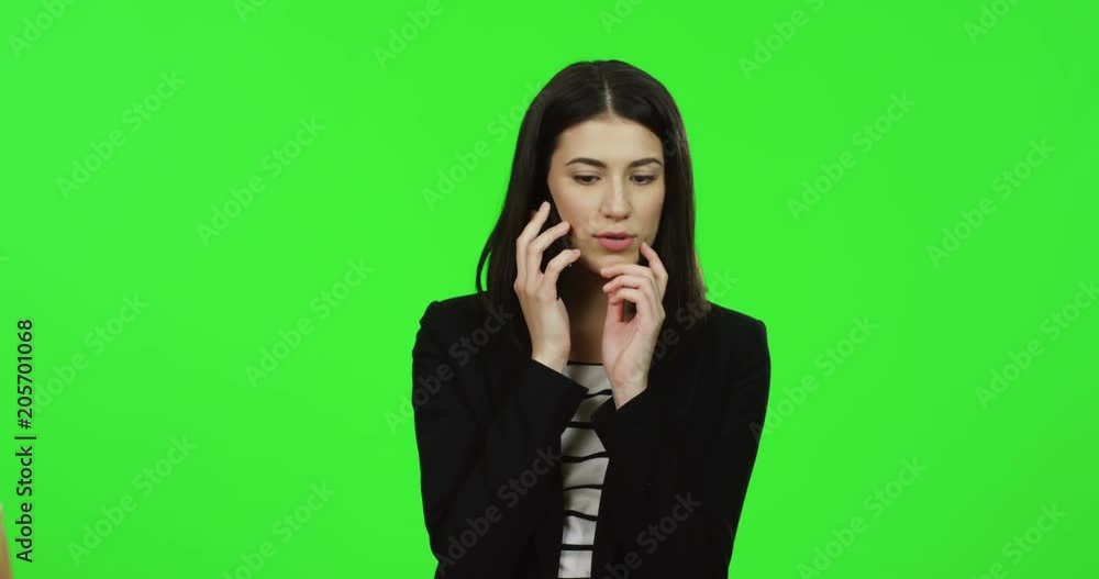 Close up of the young charming woman in the black suit speaking on the phone on the chroma key background. Green screen. Close up of the young charming woman in the black suit speaking on the phone on the chroma key background. Green screen.