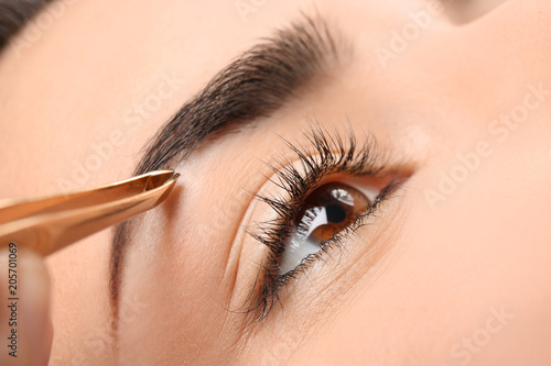Young woman having professional eyebrow correction procedure, closeup photo