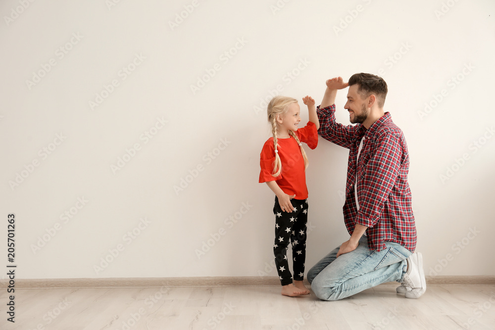 Young man and little girl measuring their height indoors - obrazy, fototapety, plakaty 